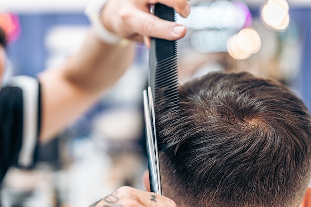 Cerrar vista tijeras y peine utilizados para cortar el cabello de un hombre adulto caucásico en un salón