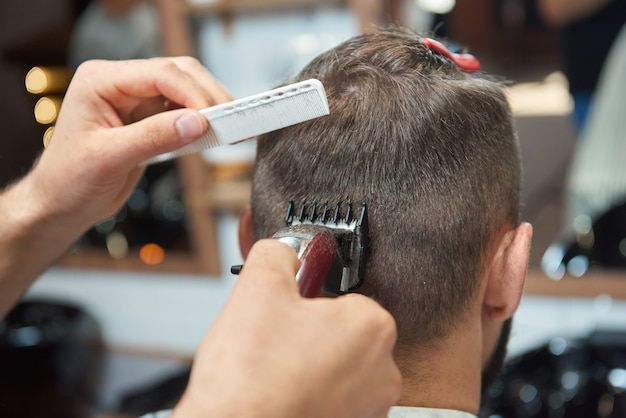 Cerrar vista trasera de un hombre obteniendo un nuevo peinado por peluquero profesional