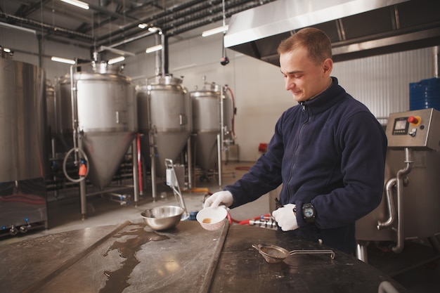 Cervecero joven alegre disfrutando de trabajar en la fábrica de cerveza