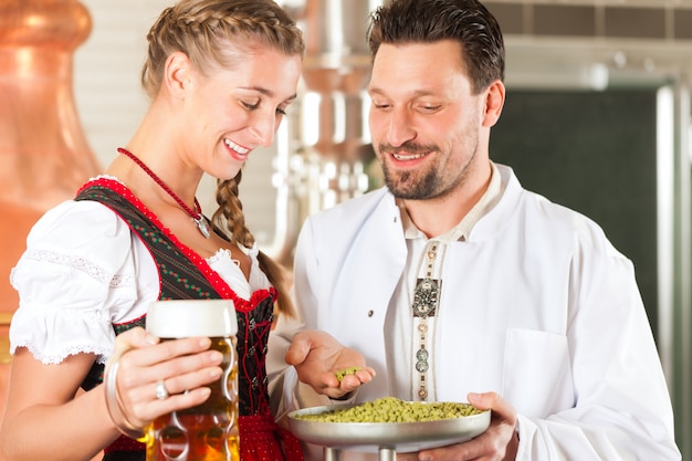 Cervecero y mujer con vaso de cerveza en cervecería