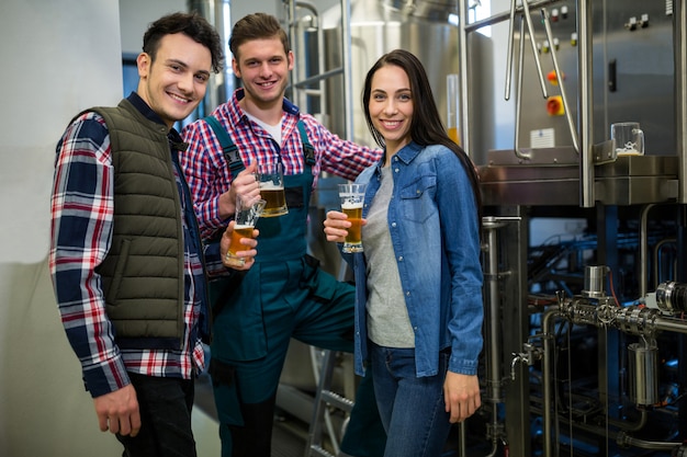 Cerveceros con vasos de cerveza en la fábrica de cerveza