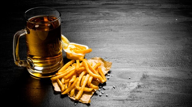 Cerveja. cerveja fresca e batatas fritas com molho de mostarda no quadro-negro.