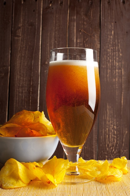 Cerveja de lager em vidro e batatas fritas na madeira