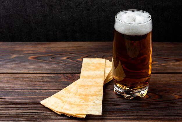 Cerveja e batatas fritas no fundo escuro de madeira.