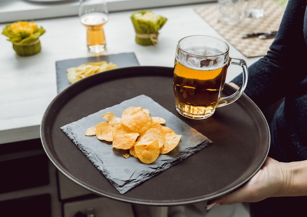 Cerveja e batatas fritas no prato grande.