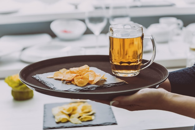 Cerveja e batatas fritas no prato grande.