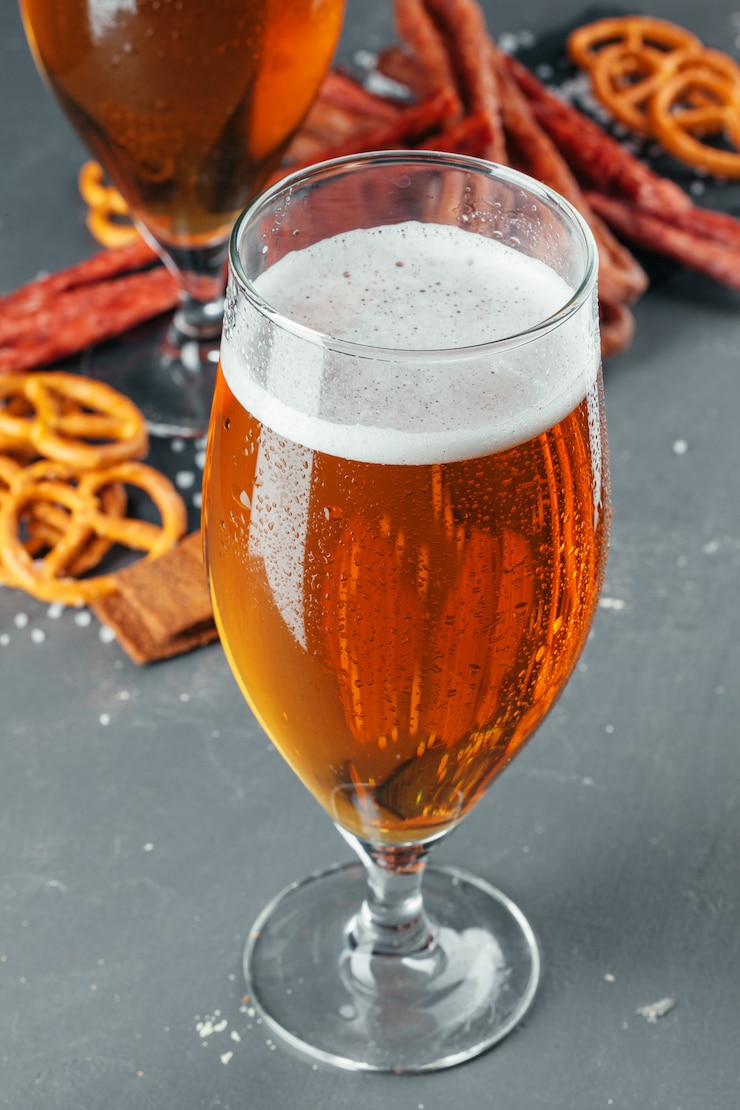 Foto cerveja e conjunto de lanches apetitosos cerveja. mesa com caneca de cerveja, tábua de madeira com salsichas