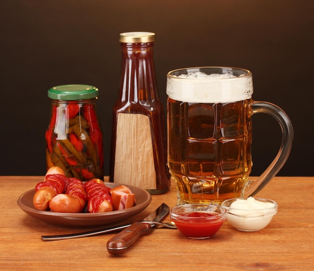 Foto cerveja e salsichas grelhadas em uma mesa de madeira em fundo castanho