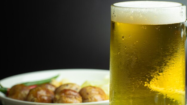 Foto cerveja em um copo ligeiramente espumante e gotas de água se agarram ao copo uma bebida alcoólica fria com um fundo como aperitivo é salsicha