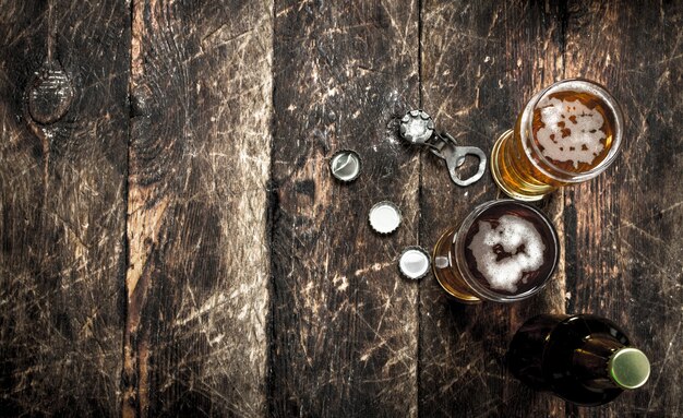 Cerveja fresca em copo com rolhas e abridor de garrafas em fundo de madeira