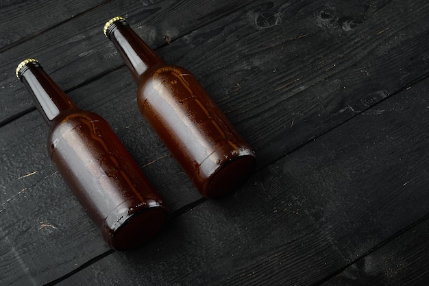 Cerveja fresca em garrafas de vidro em madeira preta