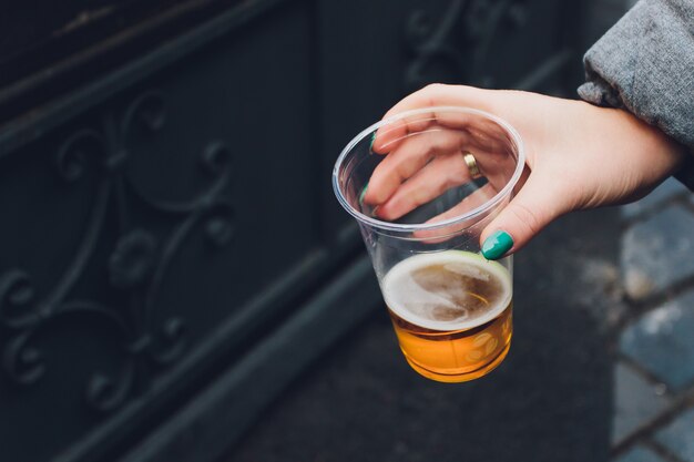 Foto cerveja fresca em um copo de plástico em uma mão.