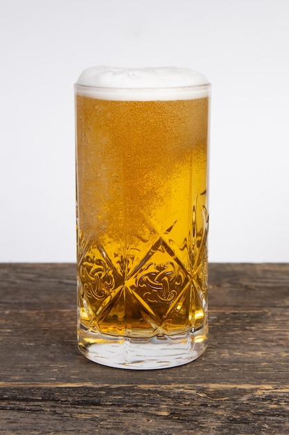 Cerveja lager em um copo em uma mesa de madeira em um fundo branco