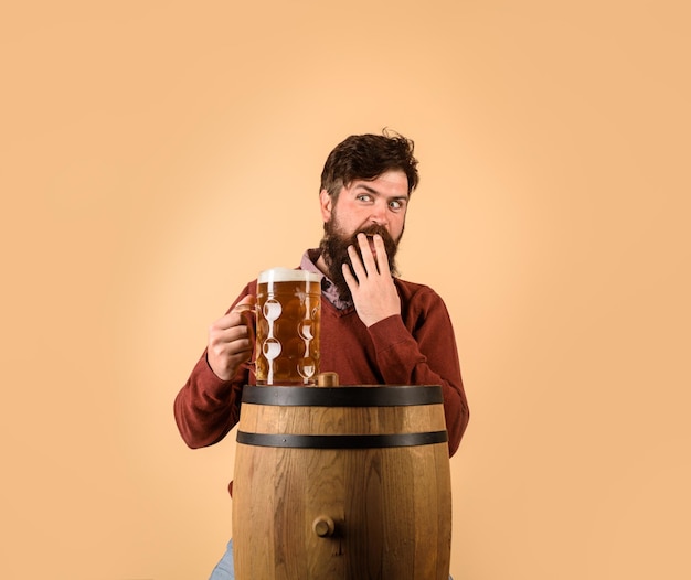 Cervejeiro barbudo atraente com barril de cerveja de madeira e caneca de cerveja no festival oktoberfest