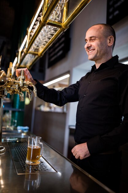 Cervejeiro encher cerveja no copo de cerveja da bomba de cerveja