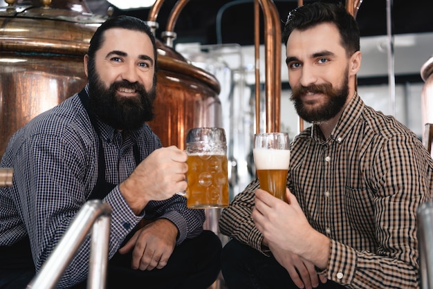 Cervejeiros felizes bebem cerveja light de vidro e caneca.