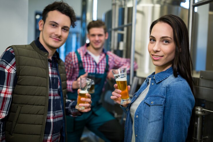 Foto cervejeiros segurando copos de cerveja na fábrica de cervejaria