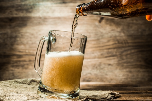 Cerveza de botella vertida en taza de pie sobre lienzo