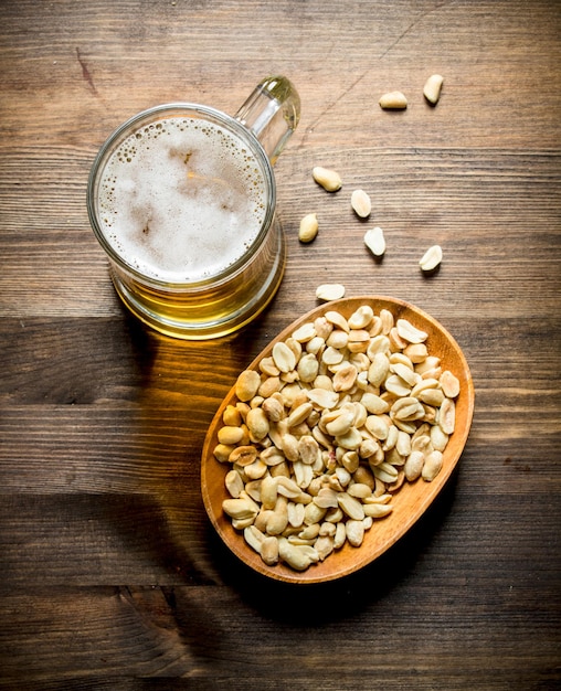 Foto cerveza y cacahuetes en el cuenco.