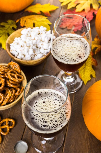 Cerveza de calabaza artesanal en vasos de cerveza con pretzels salados y palomitas de maíz.