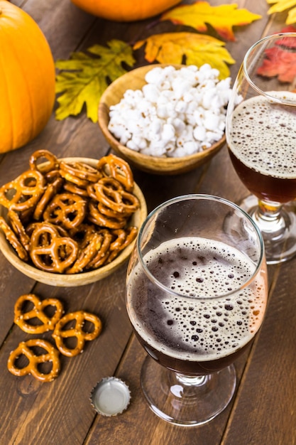 Cerveza de calabaza artesanal en vasos de cerveza con pretzels salados y palomitas de maíz.