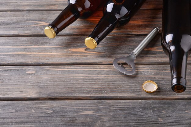 Foto cerveza fresca en botellas de vidrio y abridor sobre fondo de madera