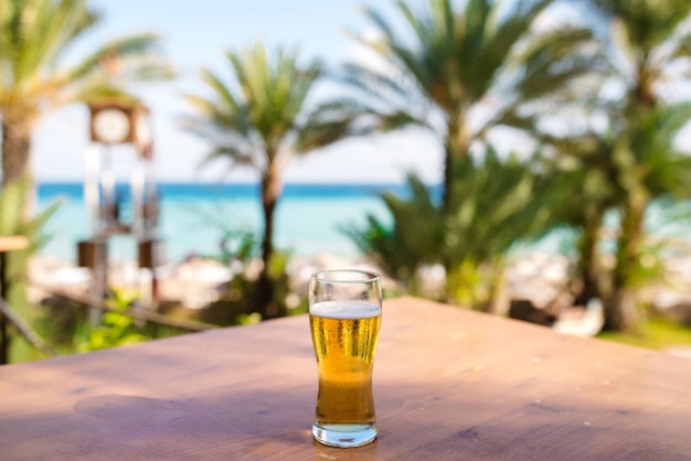 Cerveza fría y día de verano en la playa con paisaje borroso de mar