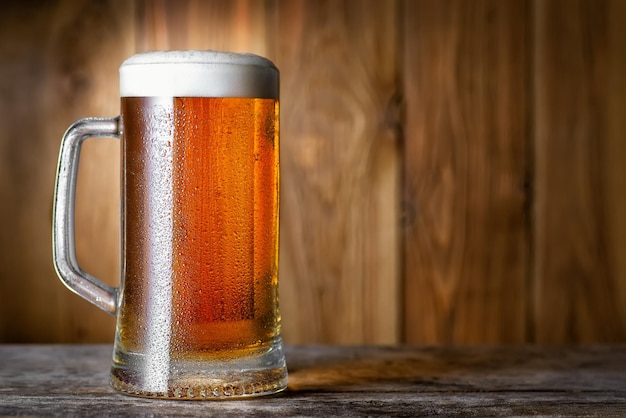 cerveza fría en taza con gotas de agua en la mesa de madera