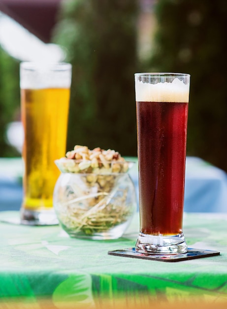 cerveza ligera y oscura con aperitivos en la mesa de la terraza del bar al aire libre