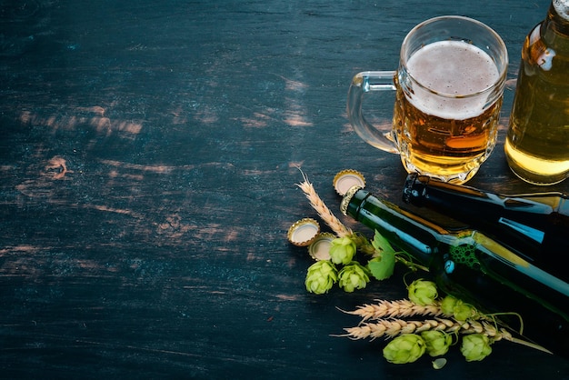 Foto cerveza y lúpulo fresco sobre un fondo de madera negra espacio libre para texto vista superior