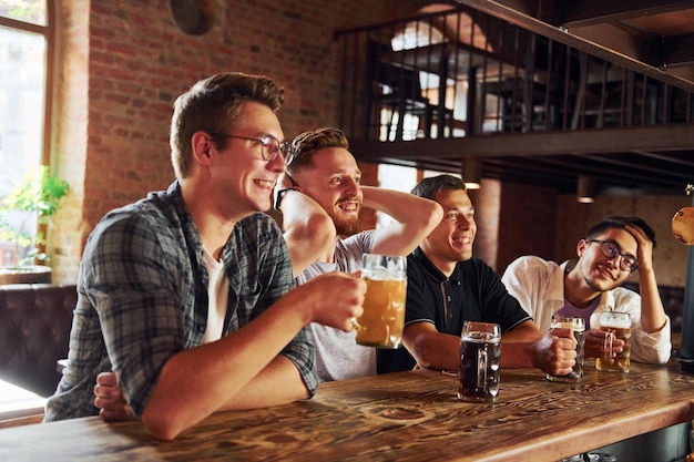 Con cerveza en las manos Gente con ropa informal sentada en el pub