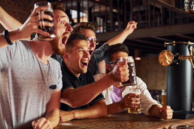 Con cerveza en las manos Gente con ropa informal sentada en el pub