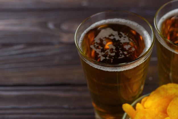 Cerveza y papas fritas Un vaso de cerveza ligera con una gran cabeza de espuma Papas fritas en un recipiente de vidrio