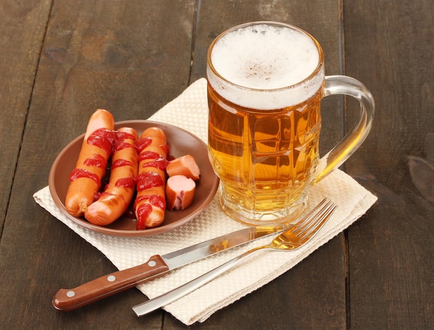 Cerveza y salchichas a la parrilla sobre fondo de madera