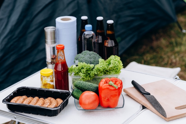 Cerveza, salchichas y verduras frescas en la mesa al aire libre