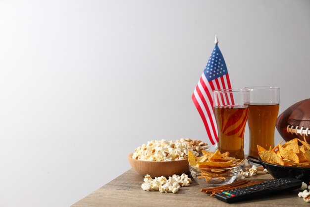 Cerveza con snacks, una pelota de rugby y una bandera americana.