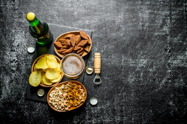 Foto cerveza y varios tipos de bocadillos en los tazones