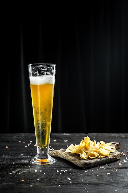 Cerveza en un vaso alto con calamares desmenuzados con bocadillos de pescado a la pimienta sobre fondo de madera Concepto de cervecería de cerveza Fondo de cerveza