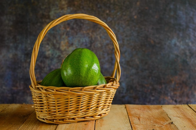 Cesta con aguacates en mesa de madera