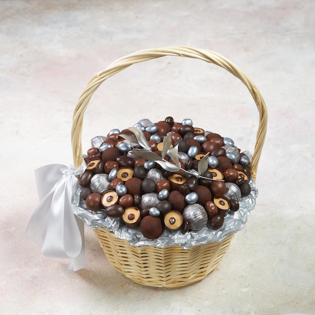 Foto cesta de color claro con caramelos de chocolate plateados