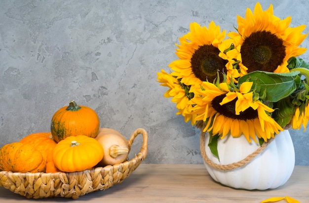 Cesta com abóboras e um buquê de flores de girassol