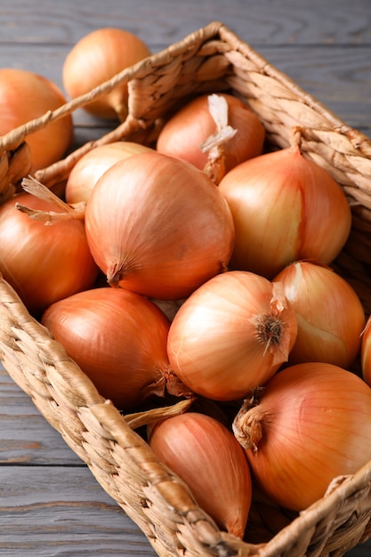 Cesta com cebola fresca em fundo de madeira