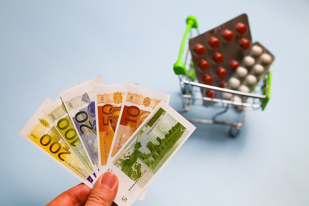 Foto cesta com comprimidos de medicamentos, cápsulas e notas de euro na mão dinheiro custo conceitual de medicamentos