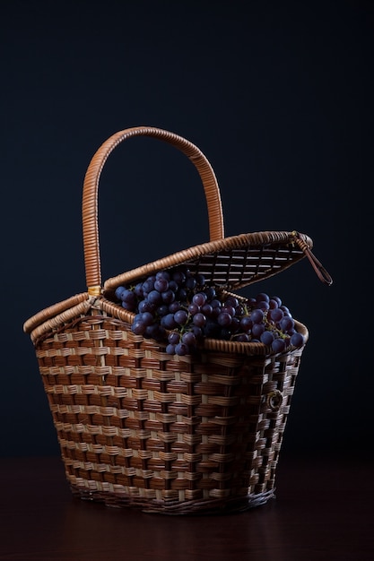 Foto cesta com uvas molhadas azuis isabella cachos no escuro