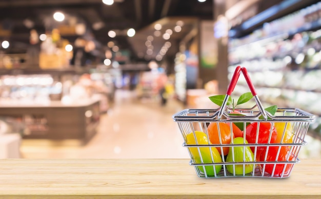 Cesta de la compra con frutas en la mesa de madera sobre la tienda de abarrotes supermercado fondo desenfocado