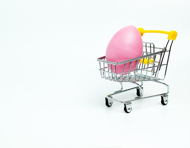 Cesta de la compra con huevos de Pascua rosas sobre un fondo blanco Compras de Pascua Espacio de copia