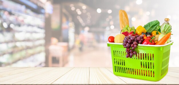 Cesta de la compra llena de frutas y verduras en la mesa de madera con supermercado fondo desenfocado borroso con luz bokeh