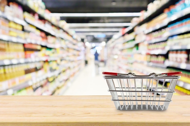 Cesta de la compra vacía en la mesa de madera sobre el fondo borroso del supermercado de la tienda de comestibles