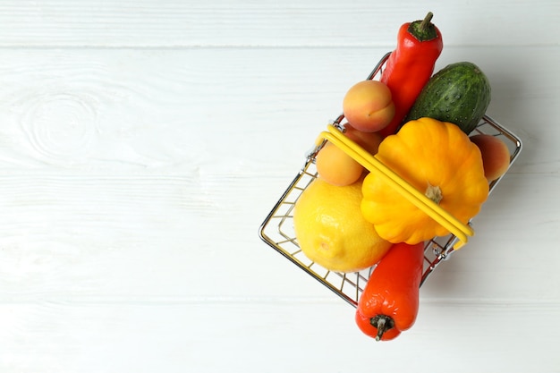 Cesta de la compra con verduras y frutas en la mesa de madera