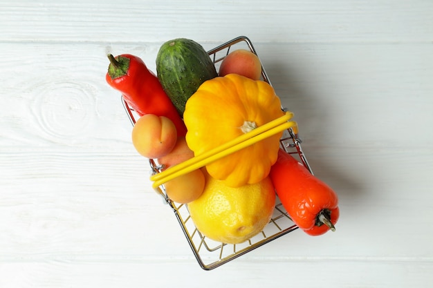 Cesta de la compra con verduras y frutas en la mesa de madera